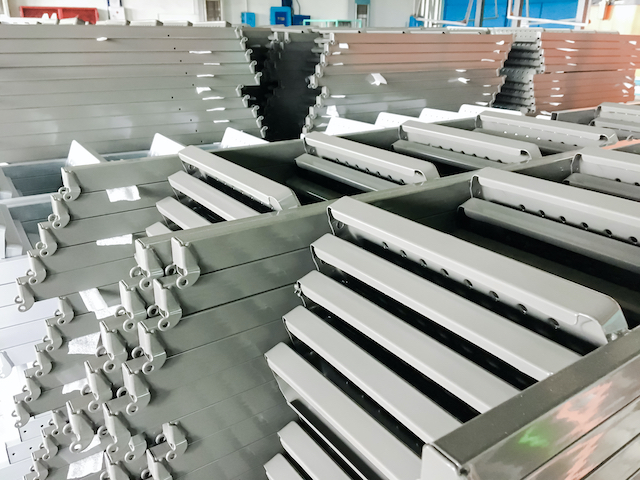 Powder coating line. Metal panels are suspended on an overhead conveyor line. Painting products in an electrostatic field.